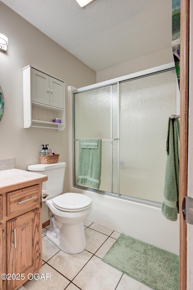 bathroom with vanity, bath / shower combo with glass door, a textured ceiling, tile patterned floors, and toilet