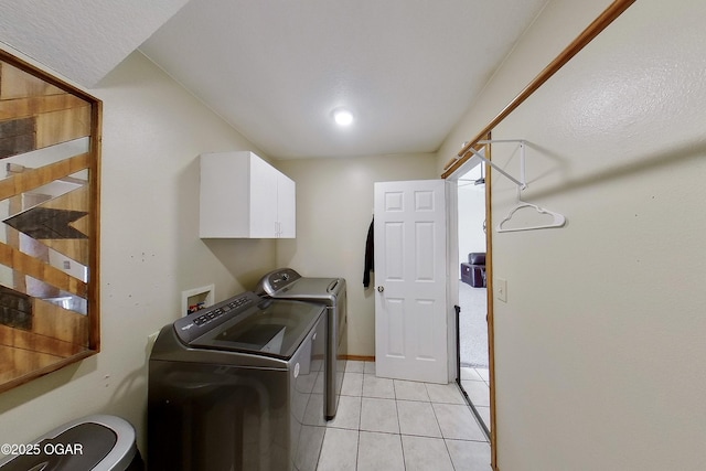 washroom featuring light tile patterned floors, cabinet space, and washing machine and clothes dryer