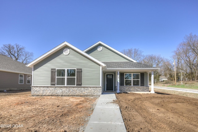 view of front of property with stone siding and roof with shingles