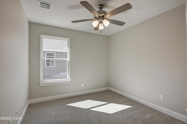 carpeted spare room featuring visible vents, a ceiling fan, and baseboards