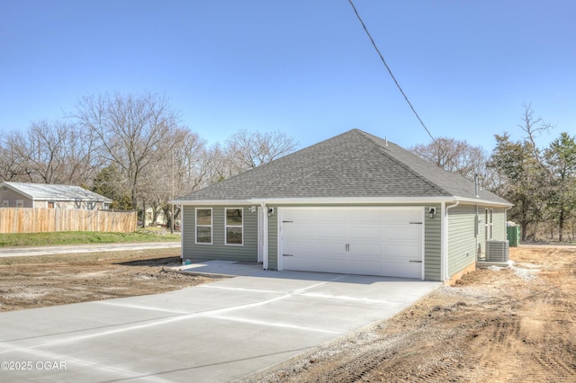 ranch-style home with fence, cooling unit, concrete driveway, an attached garage, and a shingled roof