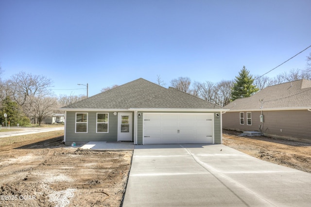 view of front of house featuring an attached garage, driveway, and roof with shingles