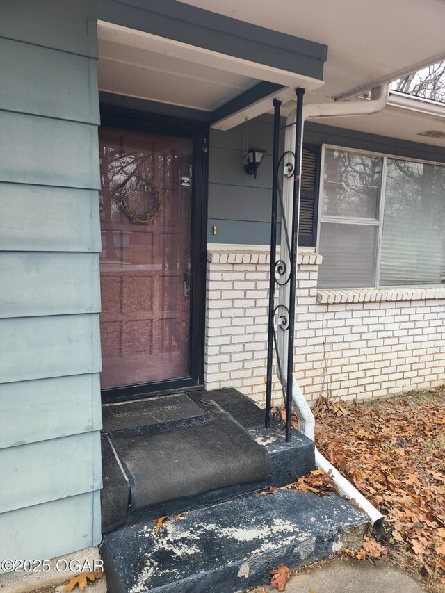 doorway to property featuring brick siding