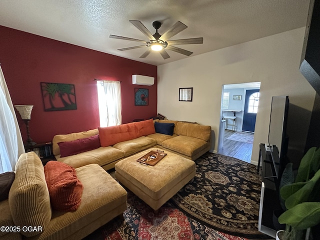 living area featuring a healthy amount of sunlight, an AC wall unit, a textured ceiling, and a ceiling fan