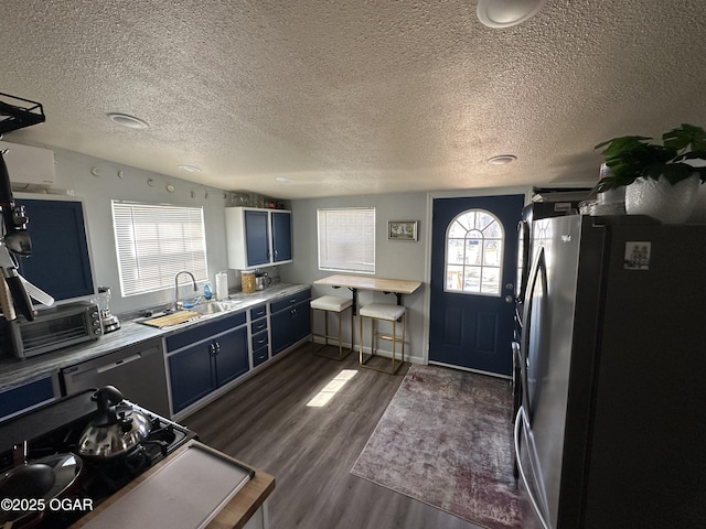 kitchen with a toaster, dark wood-style flooring, freestanding refrigerator, a sink, and light countertops