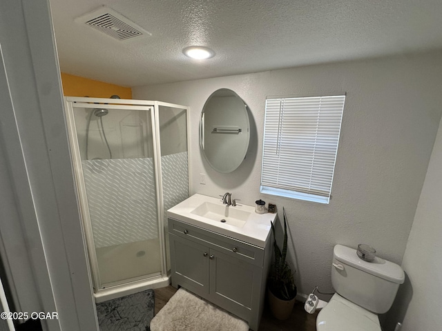 full bath with vanity, visible vents, a stall shower, a textured ceiling, and toilet