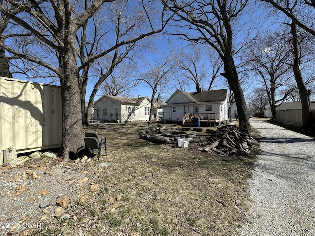 view of yard with a deck, an outdoor structure, driveway, and a shed