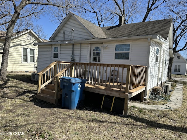 rear view of house with a deck, a chimney, and a shingled roof