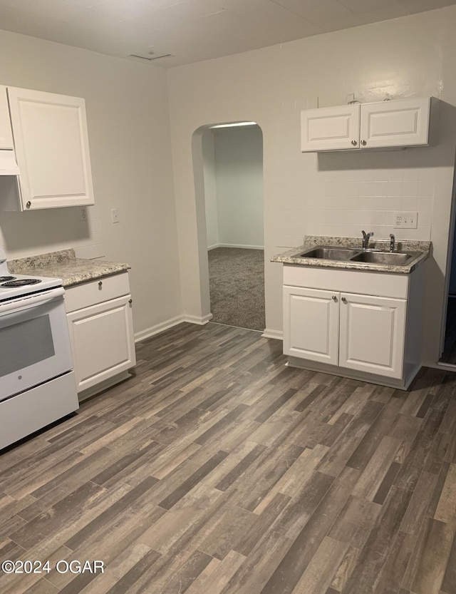 kitchen with white electric stove, arched walkways, dark wood-style flooring, a sink, and white cabinets