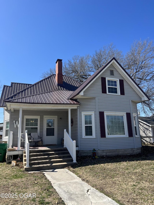 view of front of property featuring a porch, a chimney, and metal roof