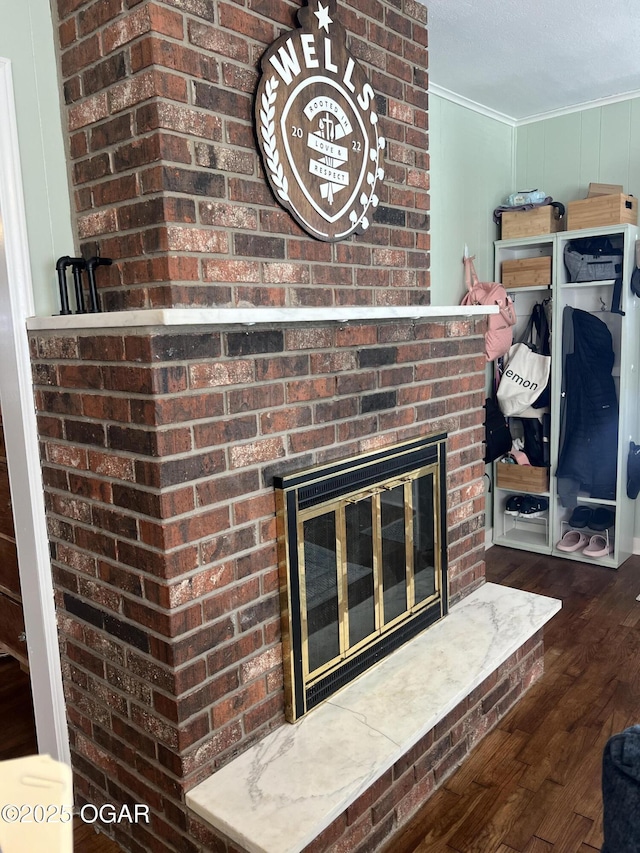 details featuring a brick fireplace, ornamental molding, and wood finished floors