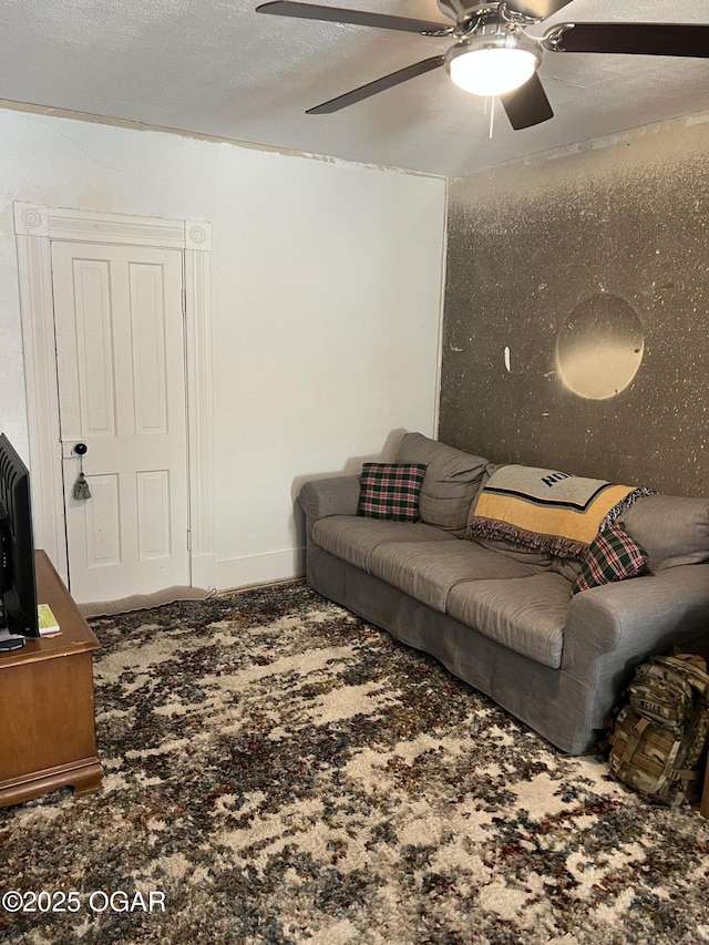 living area featuring a textured ceiling, carpet floors, ceiling fan, and baseboards