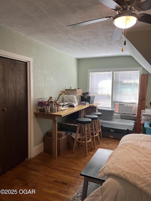 bedroom featuring cooling unit, a textured ceiling, and wood finished floors