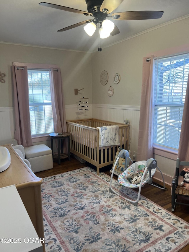 bedroom featuring crown molding, wood finished floors, and wainscoting