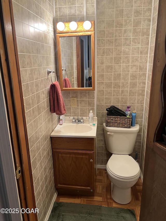 half bath featuring tile walls, toilet, and vanity