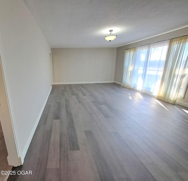 empty room featuring wood finished floors, baseboards, and a textured ceiling