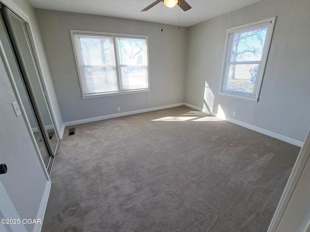 carpeted spare room featuring visible vents, baseboards, and a wealth of natural light