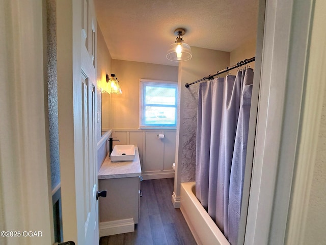 bathroom featuring vanity, wood finished floors, wainscoting, a textured ceiling, and toilet