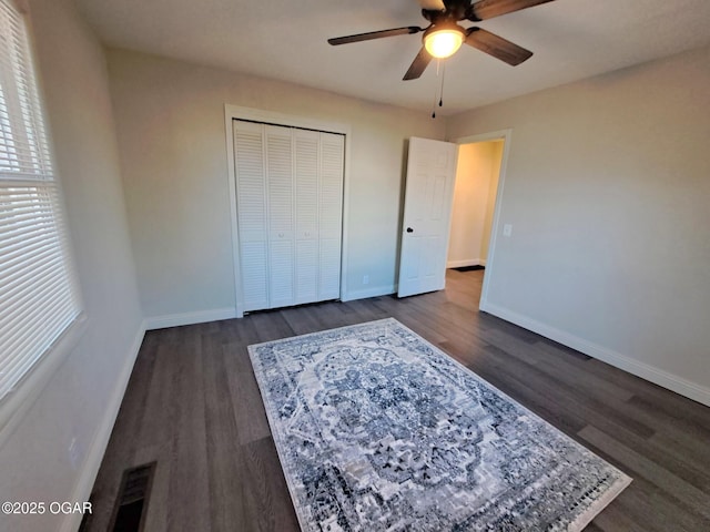 unfurnished bedroom featuring visible vents, baseboards, a closet, and dark wood-style floors