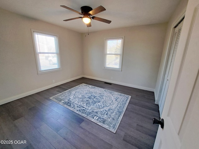 unfurnished bedroom with dark wood-type flooring, baseboards, visible vents, and a closet