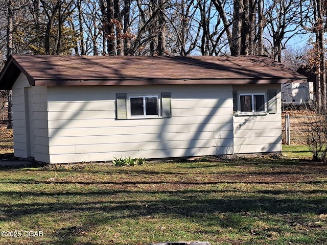 view of home's exterior featuring a lawn, roof with shingles, and fence