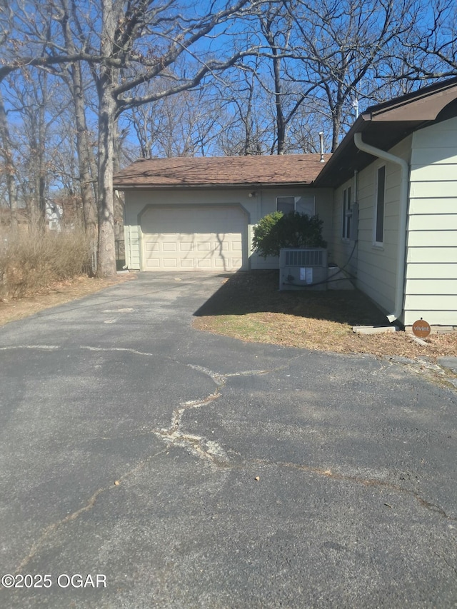 view of side of home with central AC, a garage, and driveway