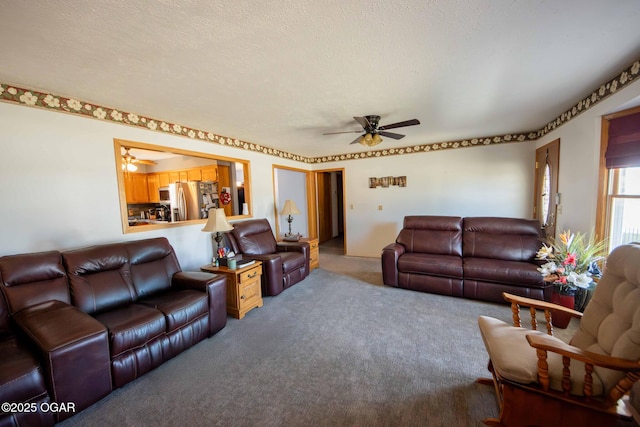 carpeted living area featuring ceiling fan and a textured ceiling