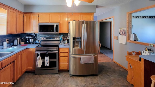 kitchen with a ceiling fan, backsplash, appliances with stainless steel finishes, light countertops, and baseboards