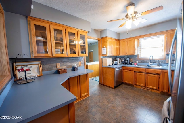 kitchen featuring brown cabinetry, stainless steel appliances, backsplash, and a sink