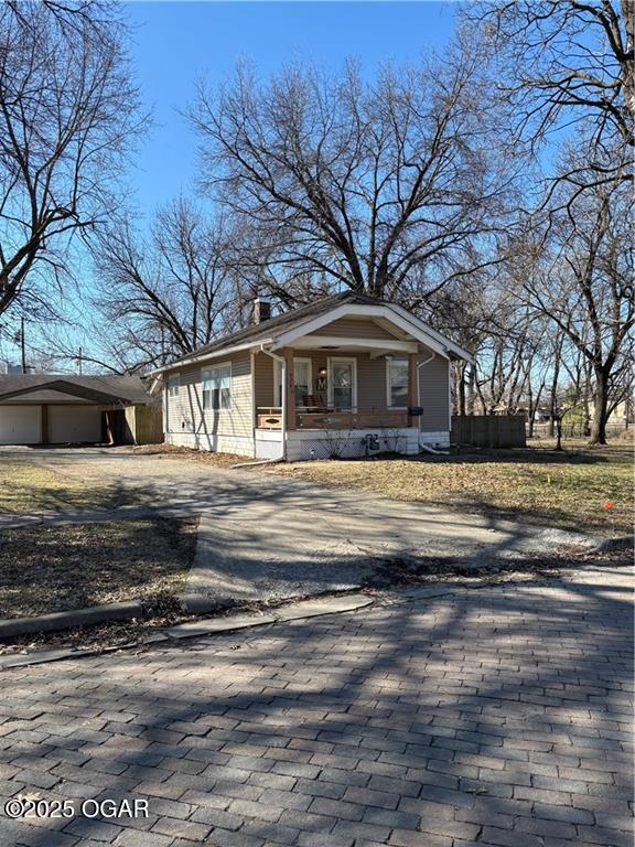 view of front of home with covered porch, driveway, and a chimney