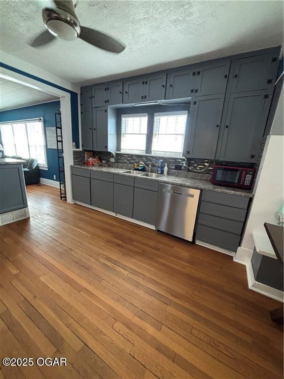 kitchen with a sink, stainless steel dishwasher, dark wood finished floors, and gray cabinets