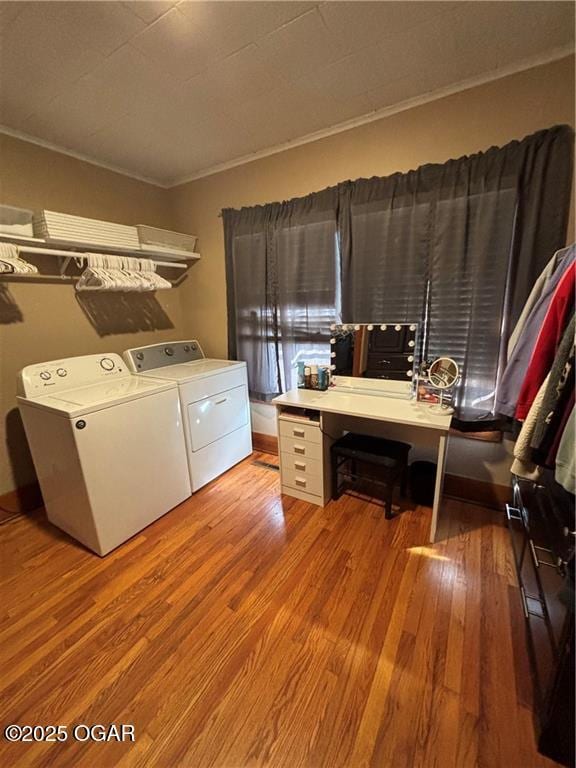 clothes washing area with wood finished floors, crown molding, separate washer and dryer, and laundry area