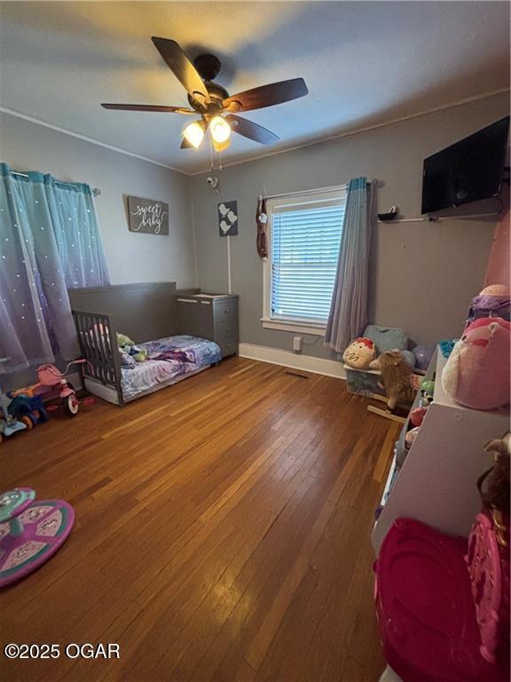 bedroom featuring hardwood / wood-style flooring, a ceiling fan, and baseboards