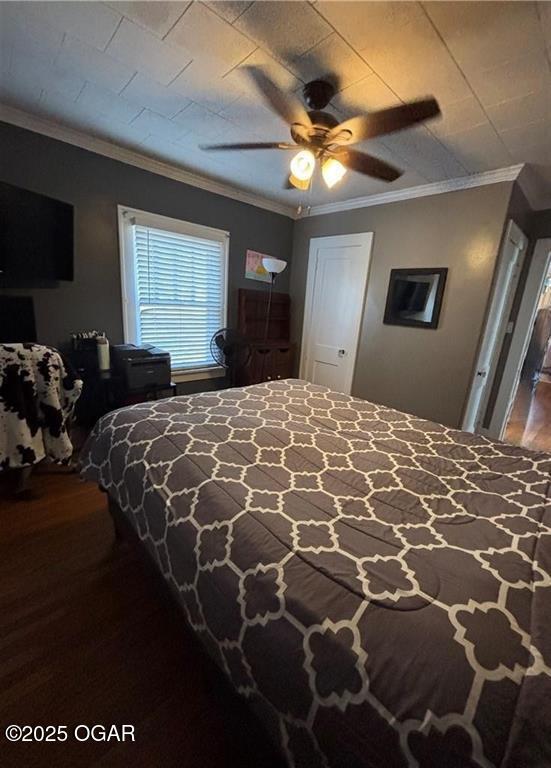 bedroom with dark wood-style flooring, ornamental molding, and a ceiling fan