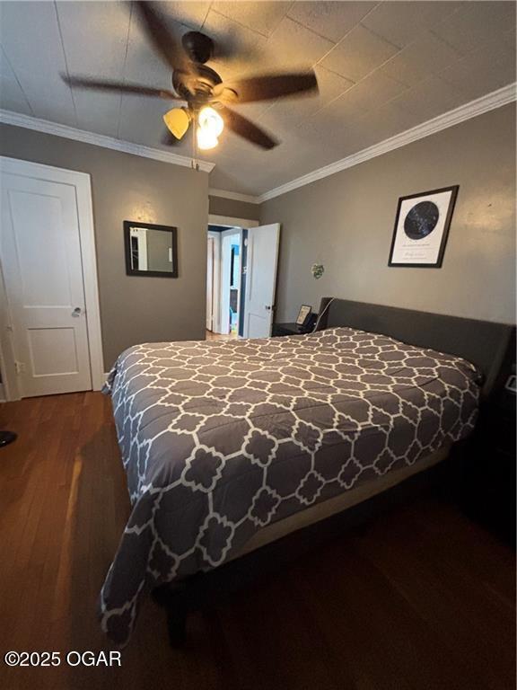 bedroom with wood finished floors, ornamental molding, and a ceiling fan