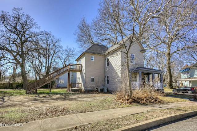 view of side of home with covered porch and stairs