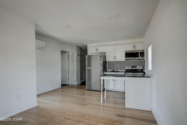 kitchen featuring a wall mounted air conditioner, white cabinetry, stainless steel appliances, light wood finished floors, and decorative backsplash