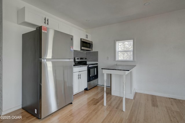 kitchen featuring tasteful backsplash, baseboards, light wood-style flooring, appliances with stainless steel finishes, and white cabinets