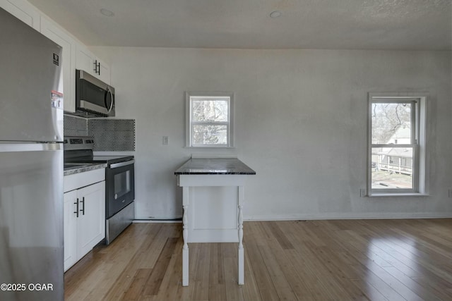 kitchen featuring dark countertops, a healthy amount of sunlight, appliances with stainless steel finishes, and white cabinets