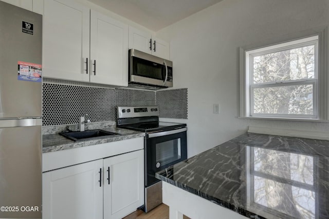 kitchen featuring a sink, backsplash, appliances with stainless steel finishes, and white cabinetry