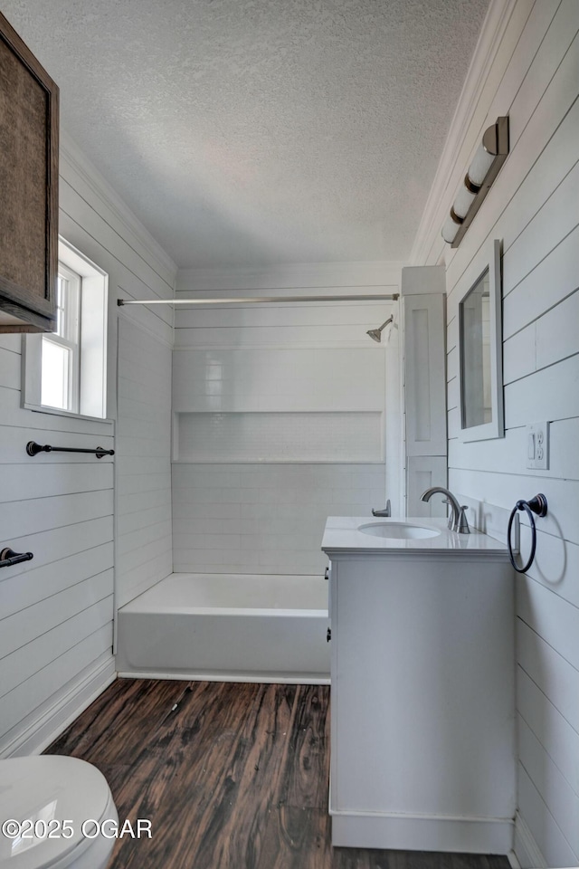 full bathroom featuring wood walls, toilet, vanity, wood finished floors, and a textured ceiling