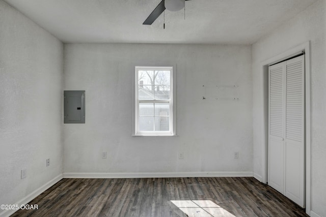 unfurnished bedroom with electric panel, wood finished floors, a closet, baseboards, and ceiling fan