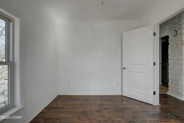 spare room with baseboards and wood finished floors