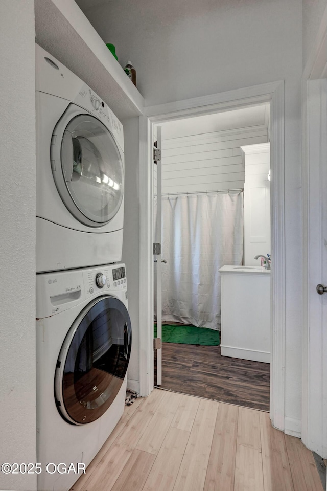 laundry room featuring wood finished floors, laundry area, and stacked washing maching and dryer