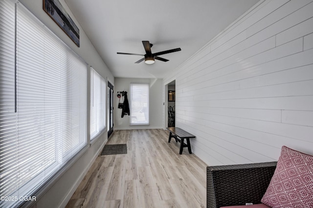 doorway with wood walls, baseboards, ceiling fan, and wood finished floors