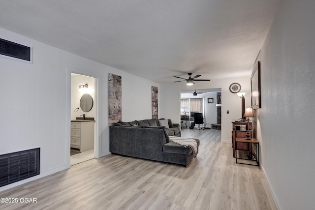 living area featuring visible vents, a ceiling fan, light wood-type flooring, and baseboards