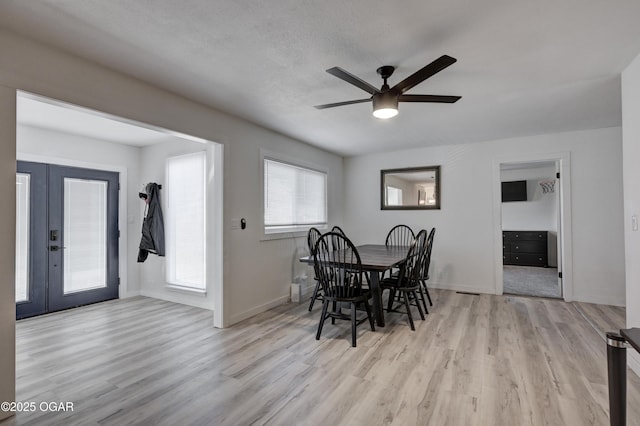 dining area featuring a ceiling fan, a textured ceiling, wood finished floors, french doors, and baseboards