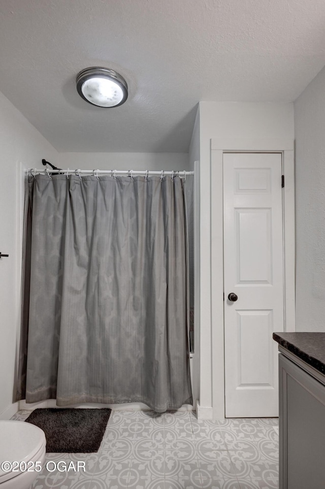 bathroom with vanity, a shower with shower curtain, a textured ceiling, tile patterned floors, and toilet