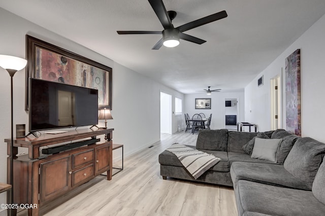 living room featuring visible vents, baseboards, light wood-type flooring, and a ceiling fan