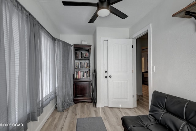 living area featuring light wood-style flooring and ceiling fan